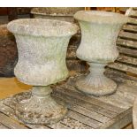 A pair of reconstituted stone campana-shaped urns on stands, decorated with ferns, diameter 34cm,