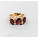 A modern 9ct gold and graduated three stone garnet set half hoop dress ring, with diamond chip