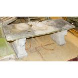 A reconstituted stone bench, with moulded rectangular top on stylised lion end supports, width