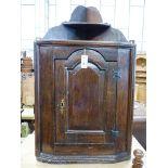 A late 17th century oak hanging corner cupboard,having shelved superstructure over an arched