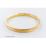 A 1930's engine turned 9ct gold bangle, interior diameter 73mm, 9 grams.