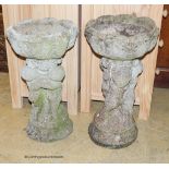 A pair of reconstituted stone circular tulip form planters on figural cherub plinths, diameter