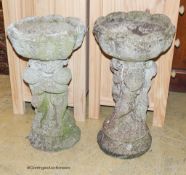 A pair of reconstituted stone circular tulip form planters on figural cherub plinths, diameter