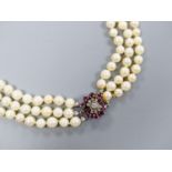 A triple strand cultured pearl necklace, with 585 white metal, ruby and diamond cluster set central