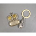 A silver plated sovereign case with faux sovereigns and a childs rattle.