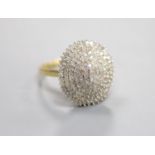 A modern 18kt and pave set diamond oval cluster dress ring, size P, gross weight 6.8 grams.