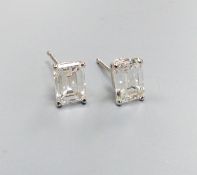A modern pair of white metal and solitaire emerald cut diamond set ear studs, gross weight 1.1