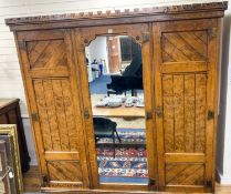 A late Victorian inlaid oak and pollard oak Aesthetic movement three door mirrored wardrobe by