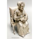 A late 19th century Hanau? white metal miniature model of an elderly lady seated in an armchair