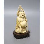 An early 20th century Japanese carved ivory okimono of Hotei, and wood stand, 15cm