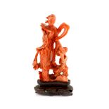 A Chinese coral figure of a female immortal standing by rockwork, mid 20th century11.5 cm high,