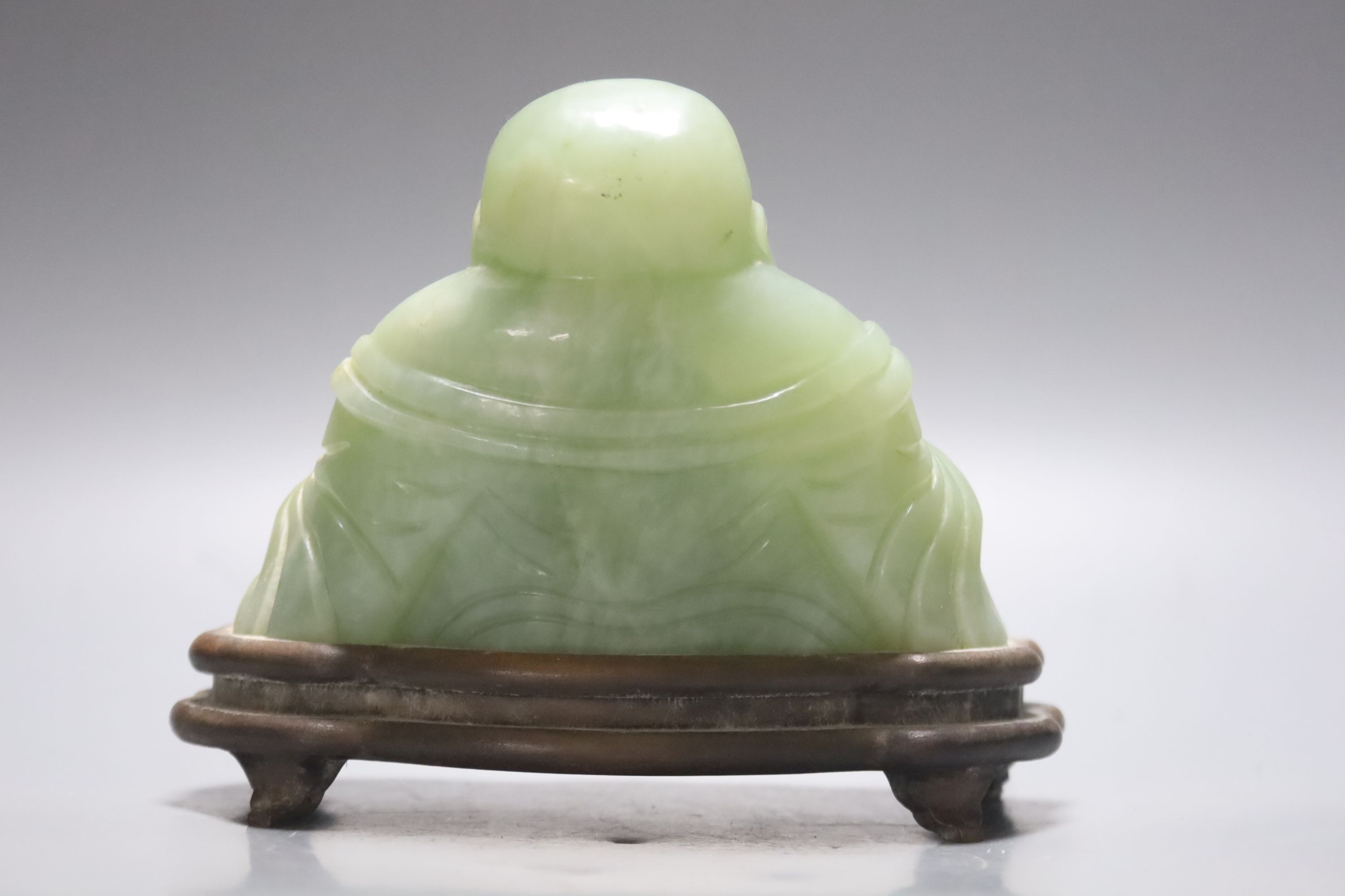 A Chinese carved bowenite jade figure of a seated Budai, H 9cm, W 13cm on carved wooden stand - Bild 2 aus 3