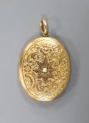 An early 20th century engraved yellow metal (stamped 9c) and split pearl set oval locket, 44mm,