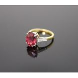 A modern 18ct gold and oval deep pink tourmaline ring, with diamond set shoulders,size Q, gross 4.3