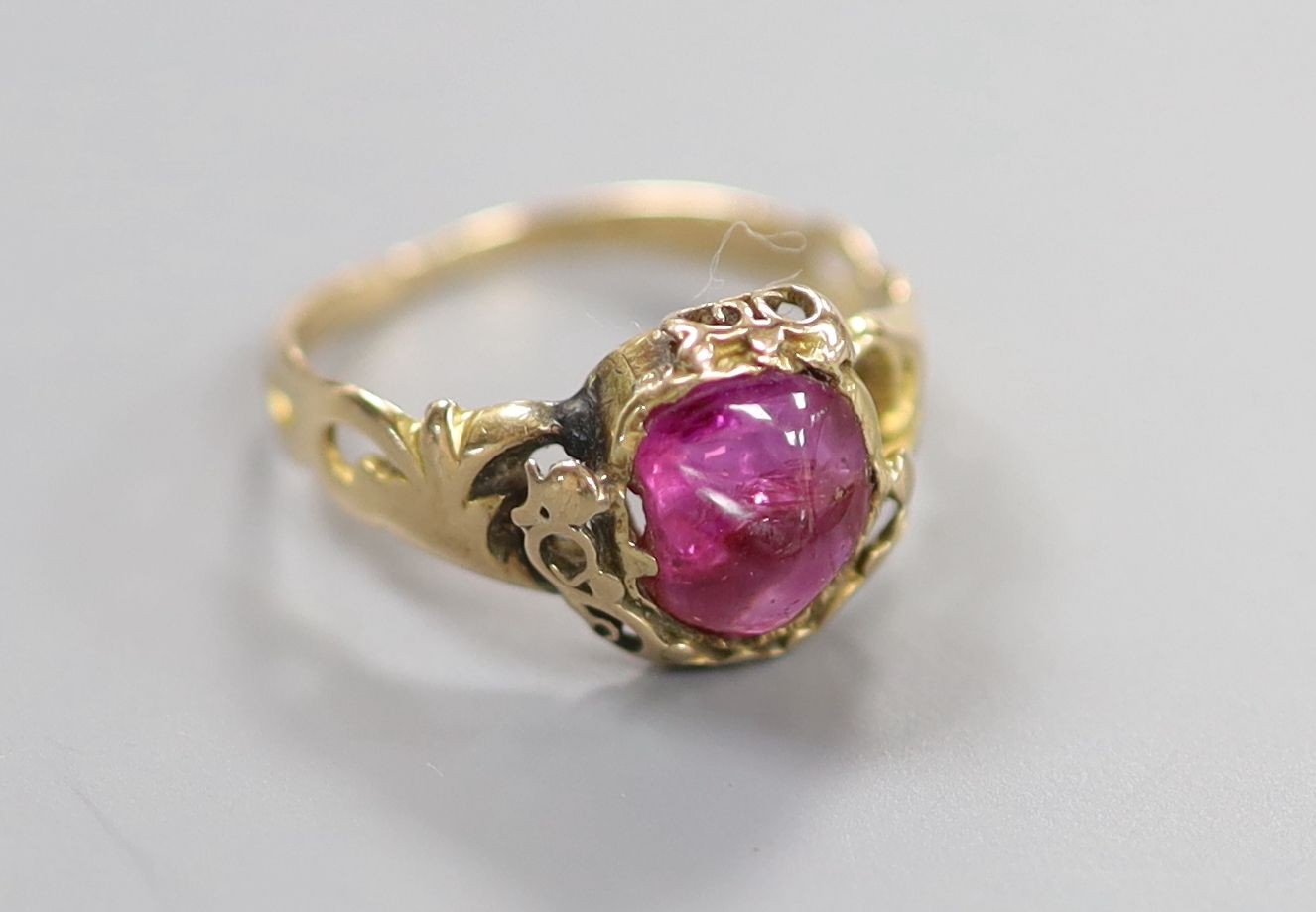 An early 20th century yellow metal and red cabochon set oval ring, size K/L, gross weight 2.4