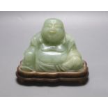 A Chinese carved bowenite jade figure of a seated Budai, H 9cm, W 13cm on carved wooden stand