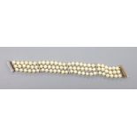 A triple strand cultured pearl bracelet, with yellow metal and diamond chip set spacers and clasp,