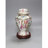 A Chinese famille rose urn shaped vase and lid, on wood plinth, 25cm