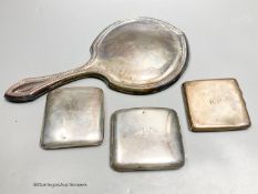 A George V silver mounted hand mirror and three silver cigarette cases.
