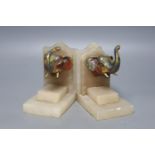A pair of 1930's alabaster book ends, each applied with a painted metal elephant head, 14cm