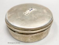 A white metal circular box and hinged cover, with enamelled applique modelled as a soldier, stamped