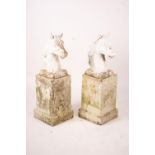 A pair of reconstituted stone horse's heads on plinth bases in the style of Austin and Seeley,