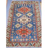 A Caucasian blue ground rug with triple medallions and geometric border, 144 x 89 cm.