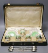 A set of six Aynsley coffee cans and saucers, with silver holders and a set of six silver spoons