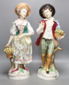 A pair of large Sitzendorf porcelain figures of a maid and a gallant, carrying baskets of fruit52cm