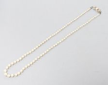 A single strand graduated cultured pearl necklace with yellow metal and gem set clasp, 49cm.