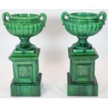 A pair of large dark green glazed terracotta fluted urns, raised on square plinths, diameter 50cm,