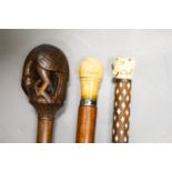 Three various walking canesIncluding two carved Ivory topped walking canes, one the cane in laid