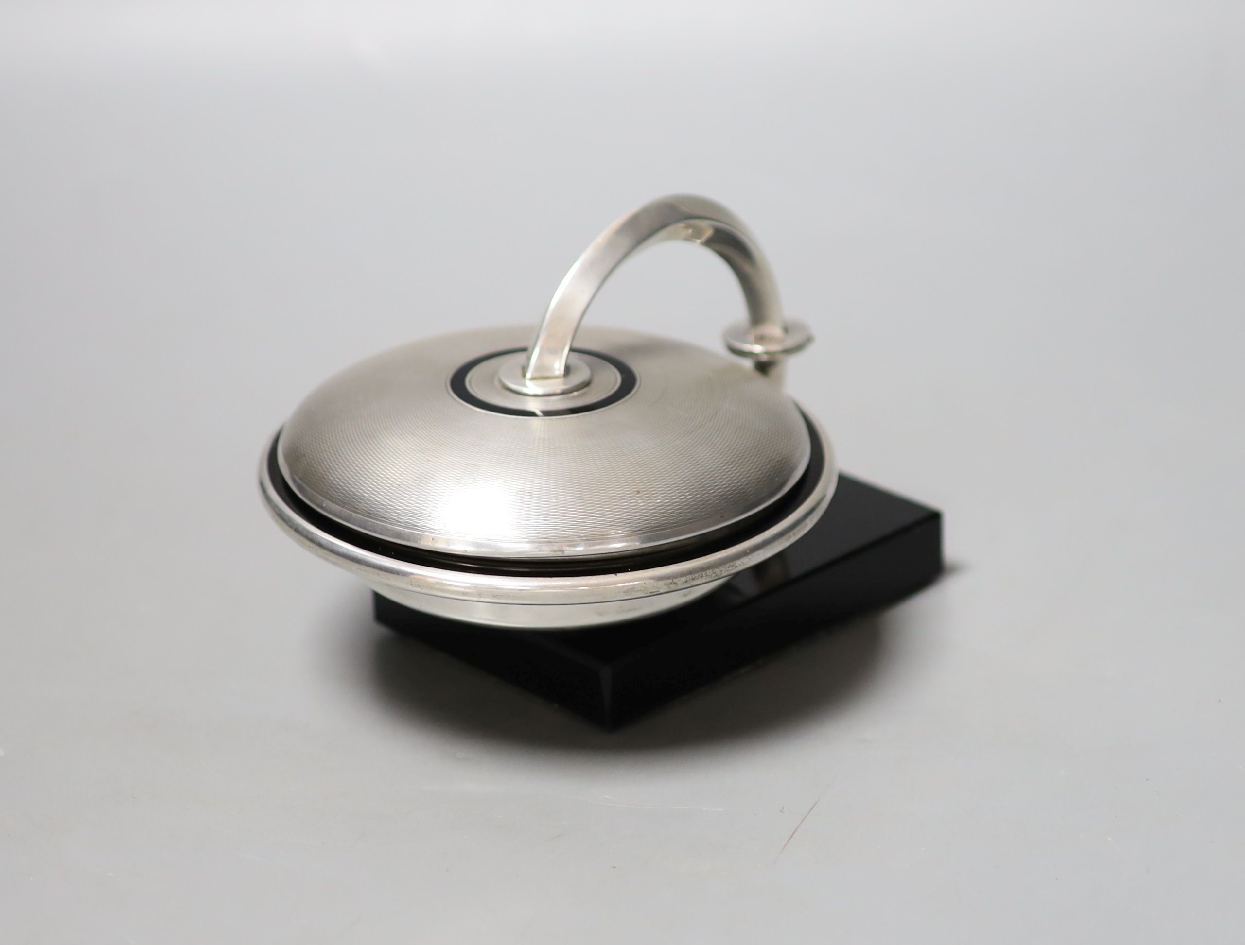 An unusual Art Deco engine turned silver and black enamel circular compact, with support arm, on