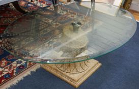 A contemporary oval glass top coffee table on simulated carved stone base, width 118cm, depth