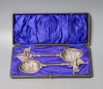 A cased pair of early 20th century Hanau white metal serving spoons, with embossed bowls and yacht