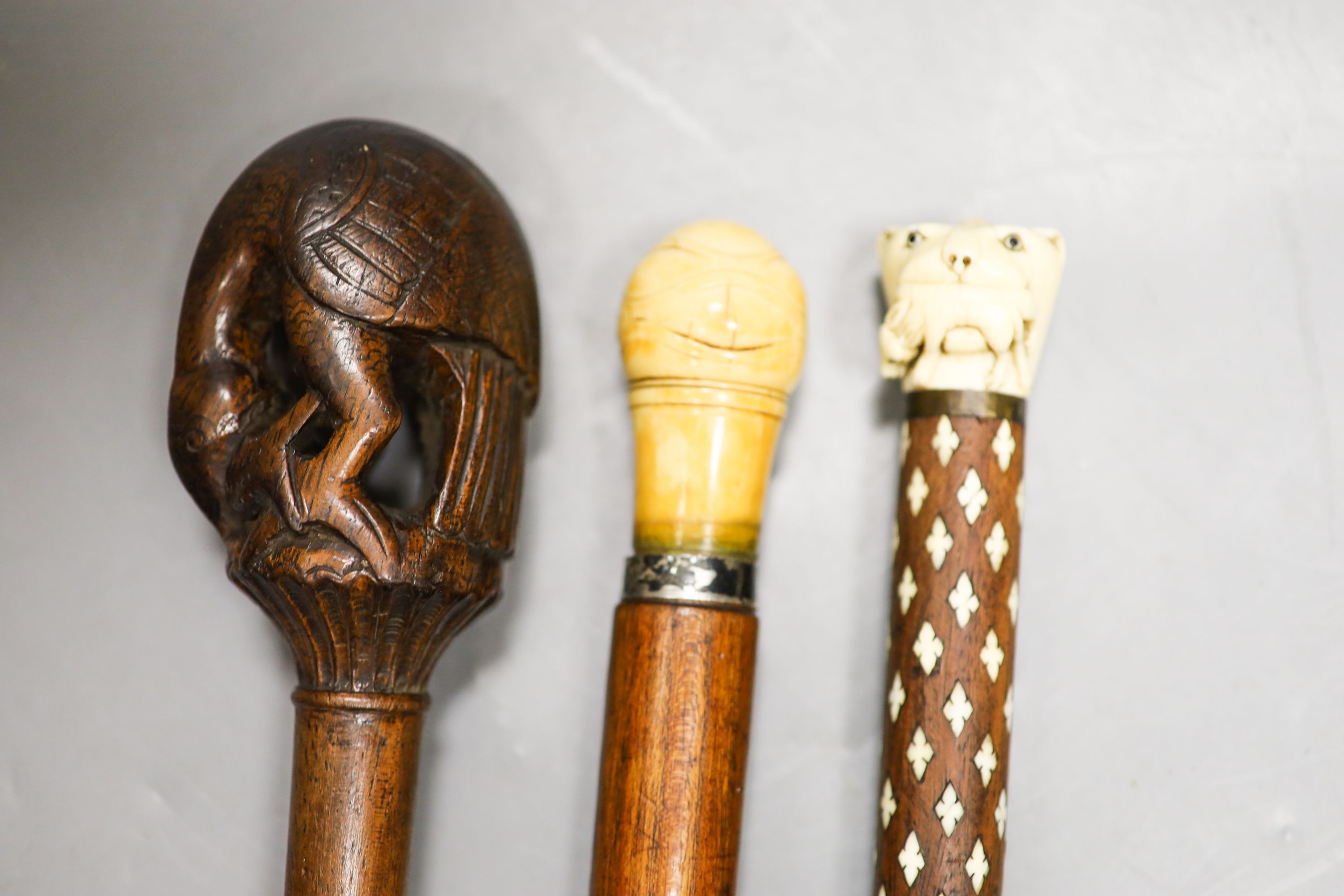 Three various walking canesIncluding two carved Ivory topped walking canes, one the cane in laid