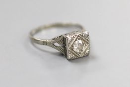 A 1920's/1930's white metal and single stone round cut diamond set square ring, with diamond set