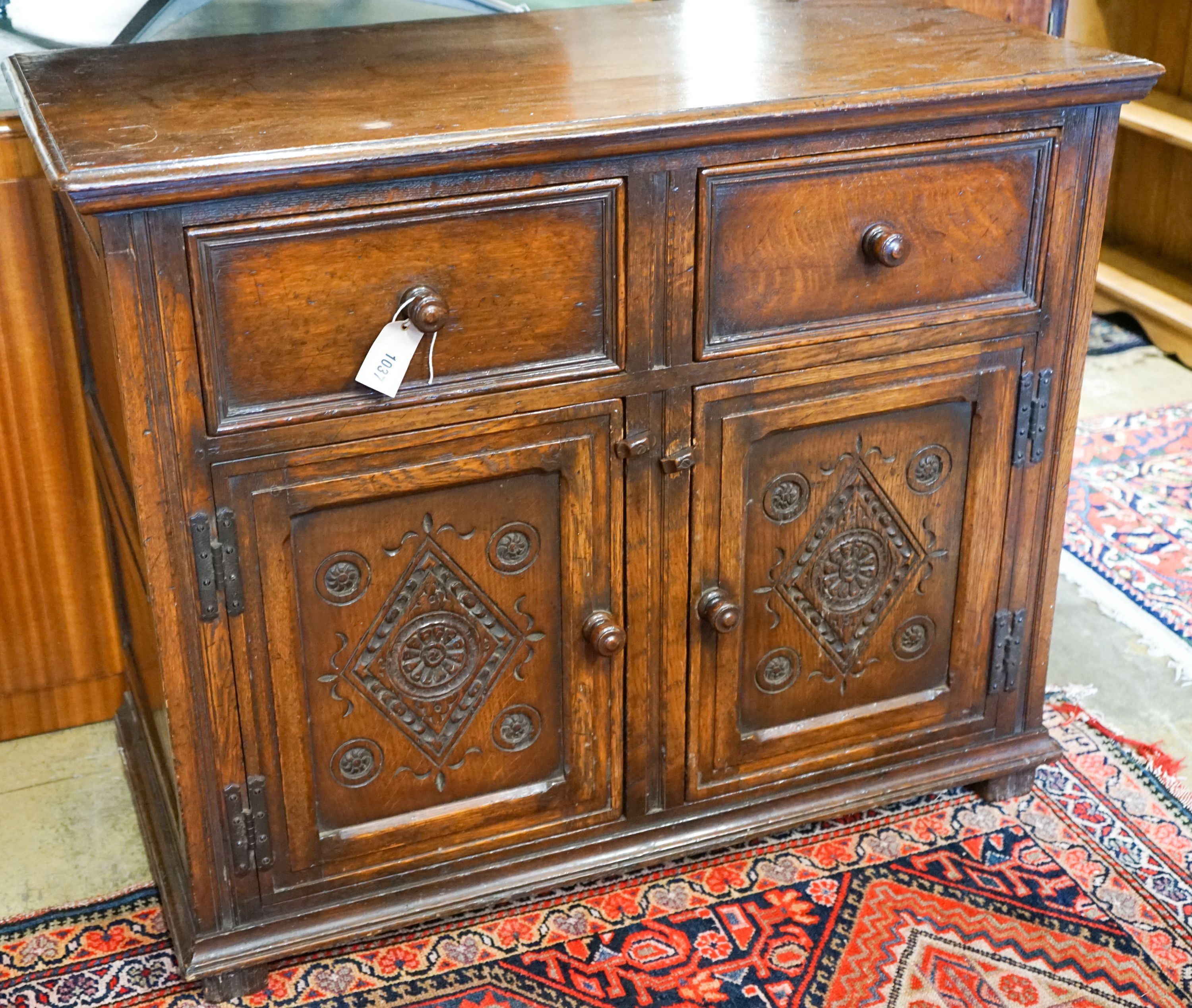 A 17th century style carved and panelled oak cupboard,fitted two drawers and two cupboards, width