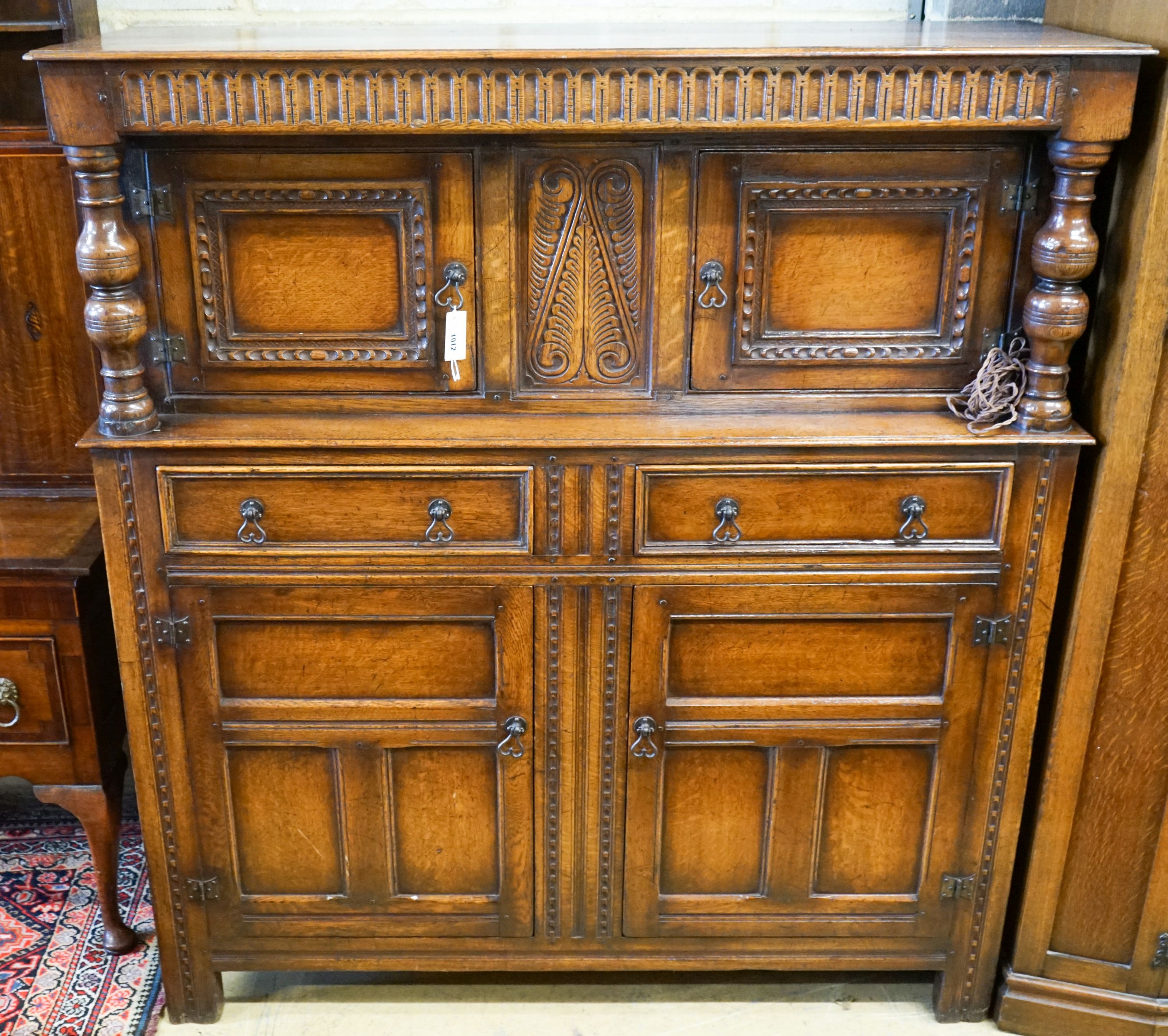 A 17th century style carved and panelled oak court cupboard,on turned supports, length 145cm,