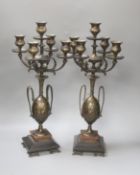 A pair of Aesthetic period bronze five light candelabra with twin handled vase supports on black and