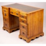 A reproduction yew inverse breakfront kneehole pedestal desk fitted green skiver, width 114cm, depth