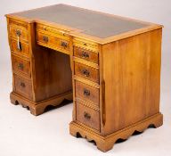 A reproduction yew inverse breakfront kneehole pedestal desk fitted green skiver, width 114cm, depth