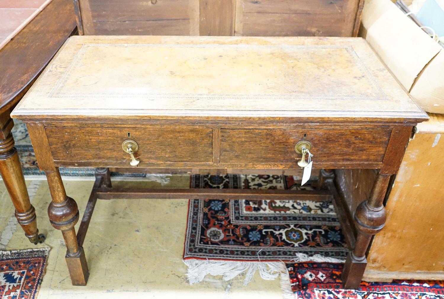A 1920's oak two drawer writing table, with a leather inset top, length 106cm, depth 52cm, height