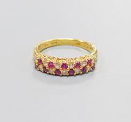 A modern 18ct gold, ruby and diamond set two row half hoop ring, size O, gross 5.3 grams.