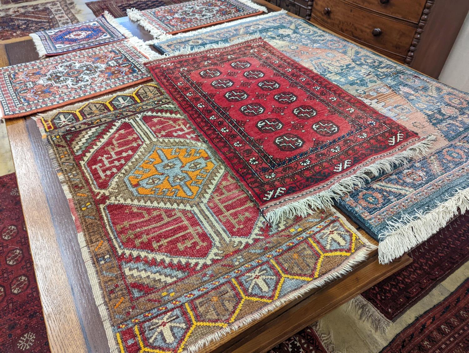 A Caucasian red ground mat, a Bokhara mat, three others and a blue ground rug, largest 136 x 80cm (
