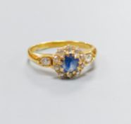 An 18ct, sapphire and diamond set circular cluster ring, with diamond set shoulders, size M, gross