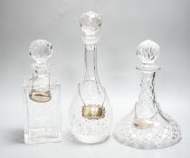 Three glass decanters, white metal labels