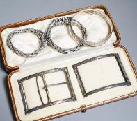 A cased Edwardian belt buckle, Goldsmiths & Silversmiths Co Ltd, London, 1908 and three bangles.