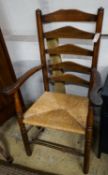 An early 19th century ash and elm rush seated ladder back elbow chair, width 63cm, depth 44cm,