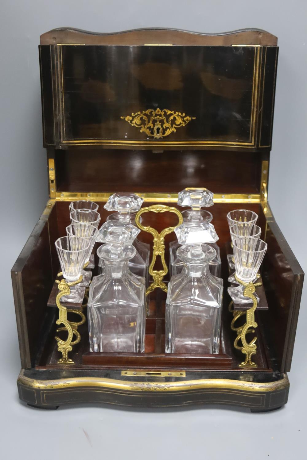 A mid-19th century French ebonised and brass-inlaid decanter case, fitted four decanters and seven